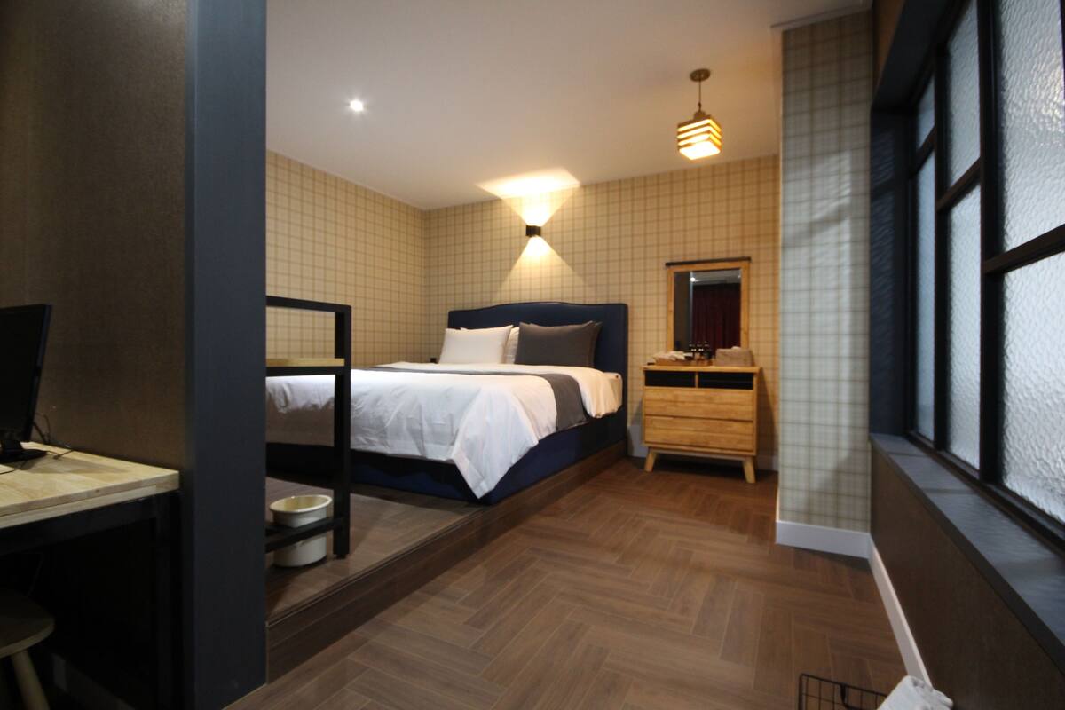 A bedroom with a bed, bedside table, and a desk with a chair.