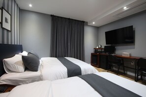 Una habitación de hotel con dos camas, un escritorio, una silla, un televisor y una cortina.