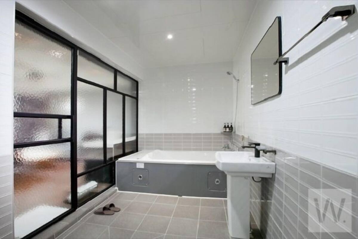 A modern bathroom with a bathtub, a sink, and a large mirror.