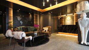 A modern lobby with a sofa, armchair, and a decorative white sculpture.