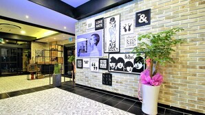 A lobby with a brick wall decorated with various posters and a large potted plant. - Instar Hotel Yangsan (Yangsan)