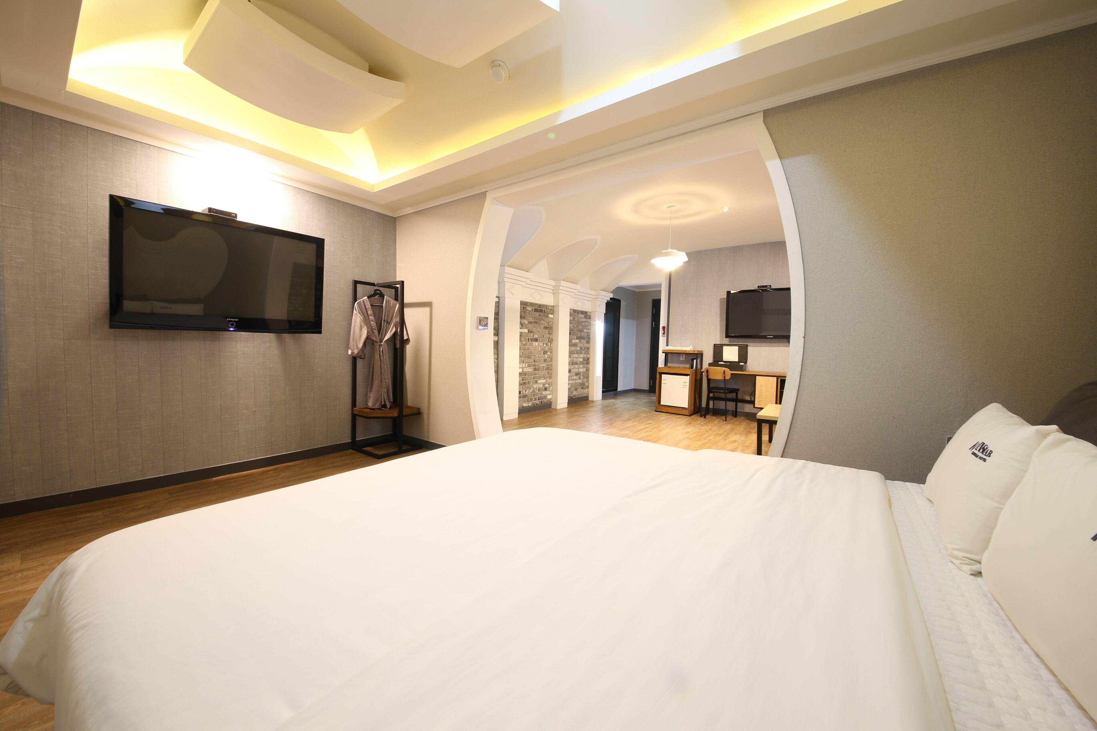 Una habitación de hotel con una cama grande, un televisor montado en la pared y un escritorio con una silla.
