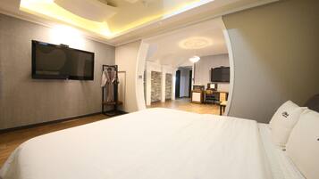 Una habitación de hotel con una cama grande, un televisor montado en la pared y un escritorio con una silla.
