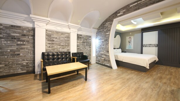 A bedroom with a bed, a bench, and a seating area with a sofa and chairs. - Instar Hotel Yangsan (Yangsan)