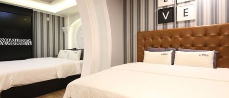 A hotel room with two beds, a large tufted headboard, and a 'LOVE' sign on the wall.