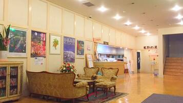 A lobby with a reception desk, a sofa, and chairs. There are posters on the wall and a cabinet with books.