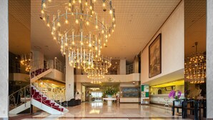En rummelig lobby med en stor lysekrone, en trappe og en reception.