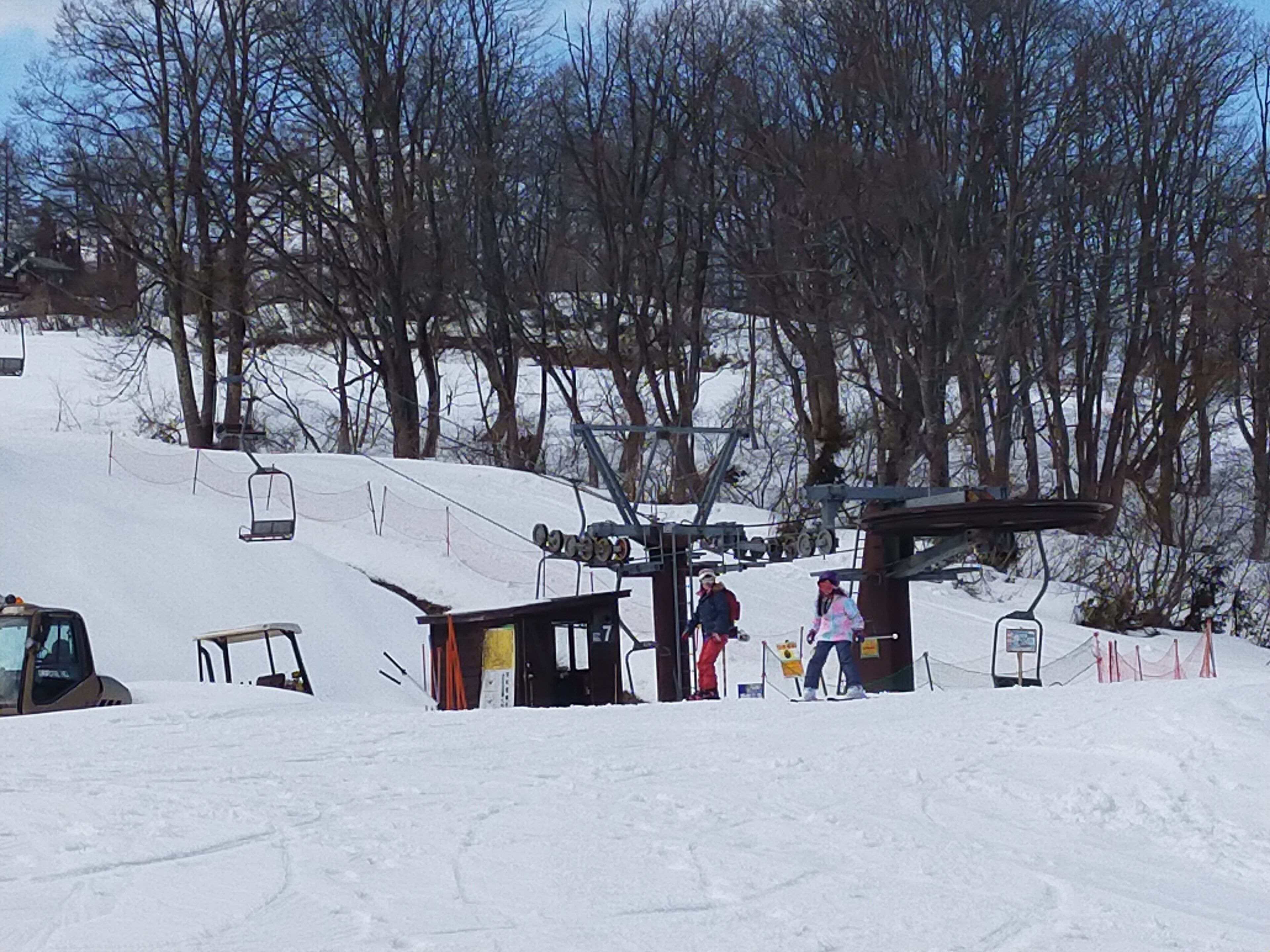A ski lift station with a chairlift, a small shelter, and a signboard.