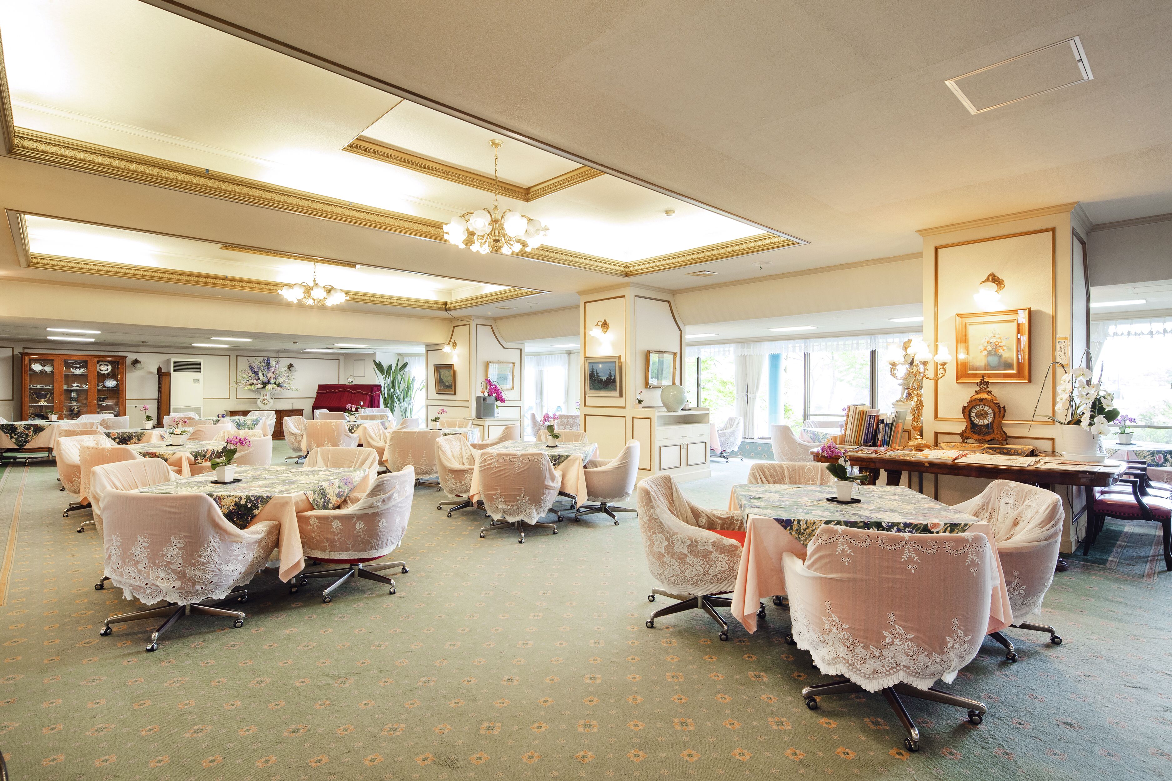 A spacious room with multiple tables and chairs, a chandelier, and framed artwork on the walls.
