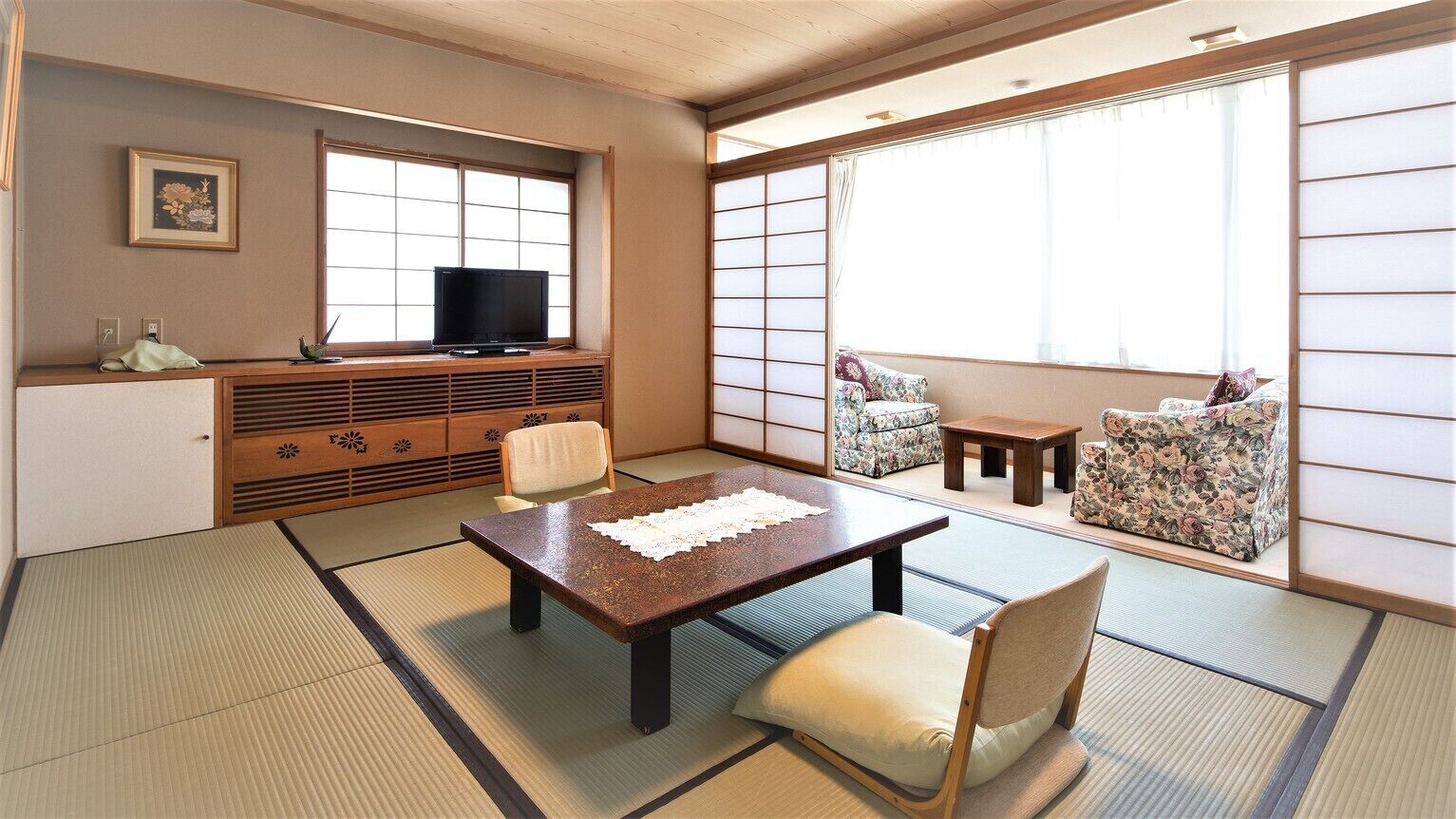 Une pièce de style japonais traditionnel, avec un sol recouvert de tatamis, une table basse, un téléviseur et un canap é.