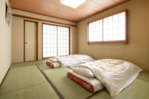 Une pièce de style japonais traditionnel, avec un sol recouvert de tatamis, deux nattes de tatami, un plafond en bois et des portes coulissantes.