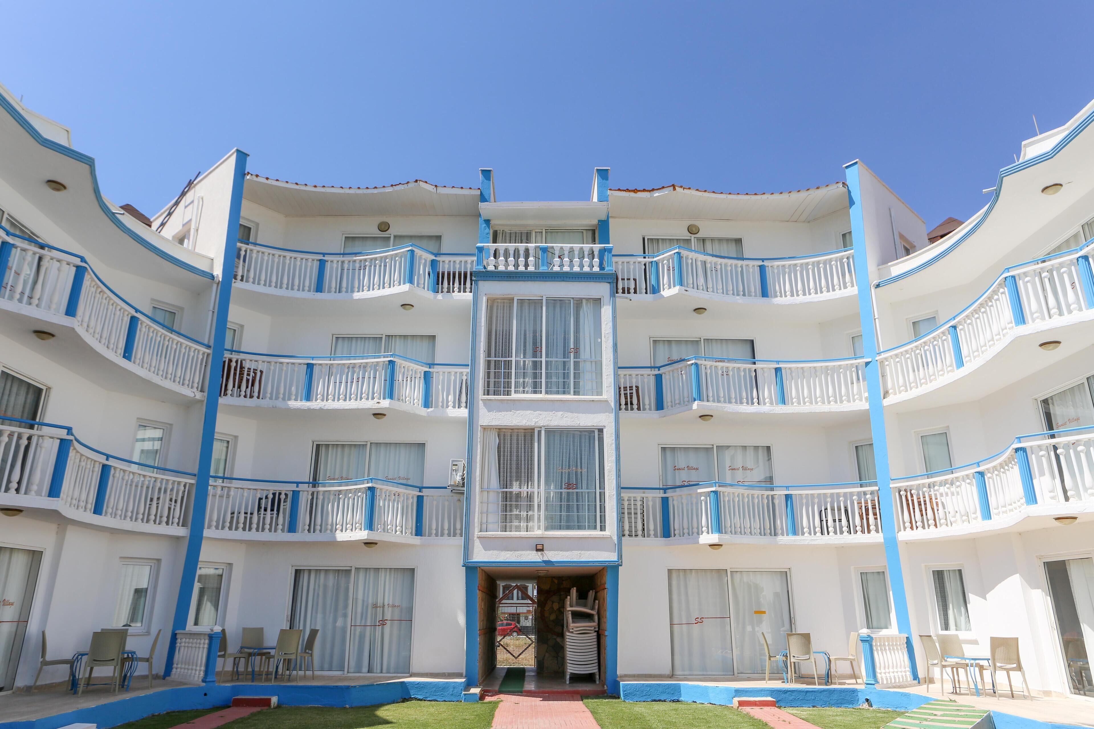 Un hotel de varios pisos con balcones, una entrada principal y zonas de estar al aire libre.