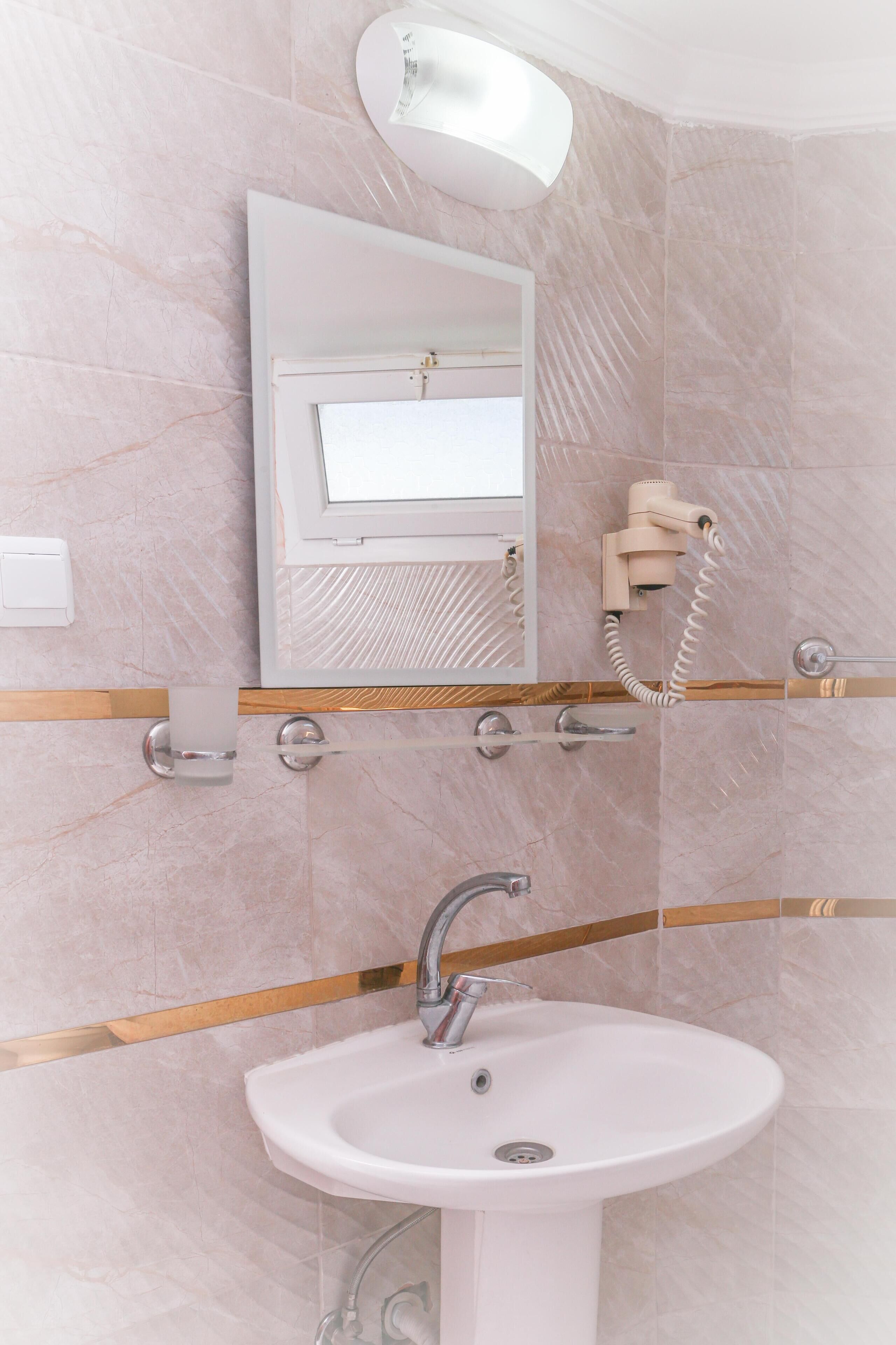 A bathroom with a white sink, a mirror, a hairdryer, and a towel rack.