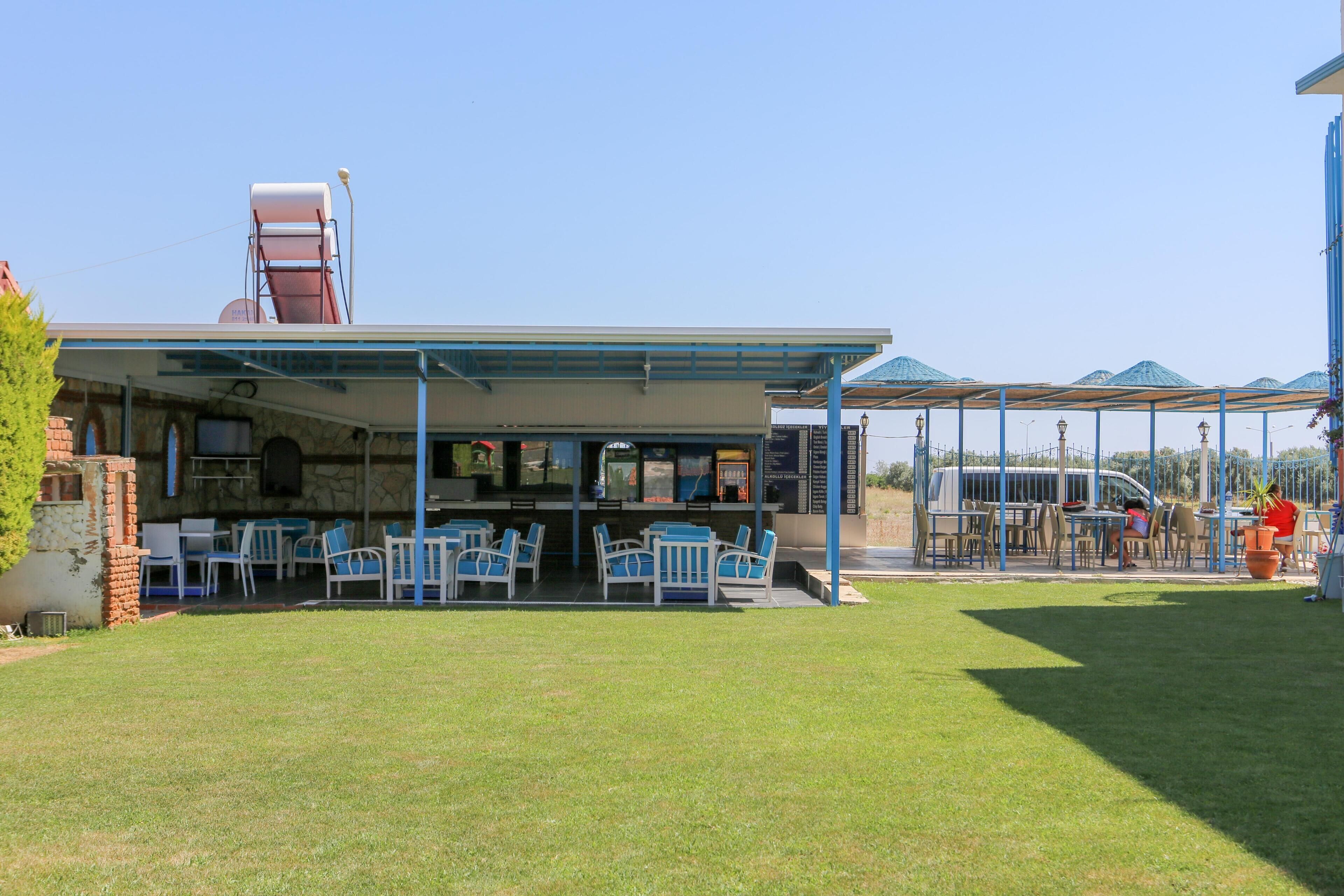 A covered outdoor seating area with tables and chairs, a water fountain, and a small brick structure.