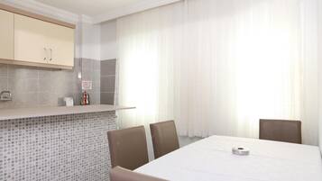 A modern kitchen with a tiled backsplash, a built-in oven, and a dining area with a table and chairs.