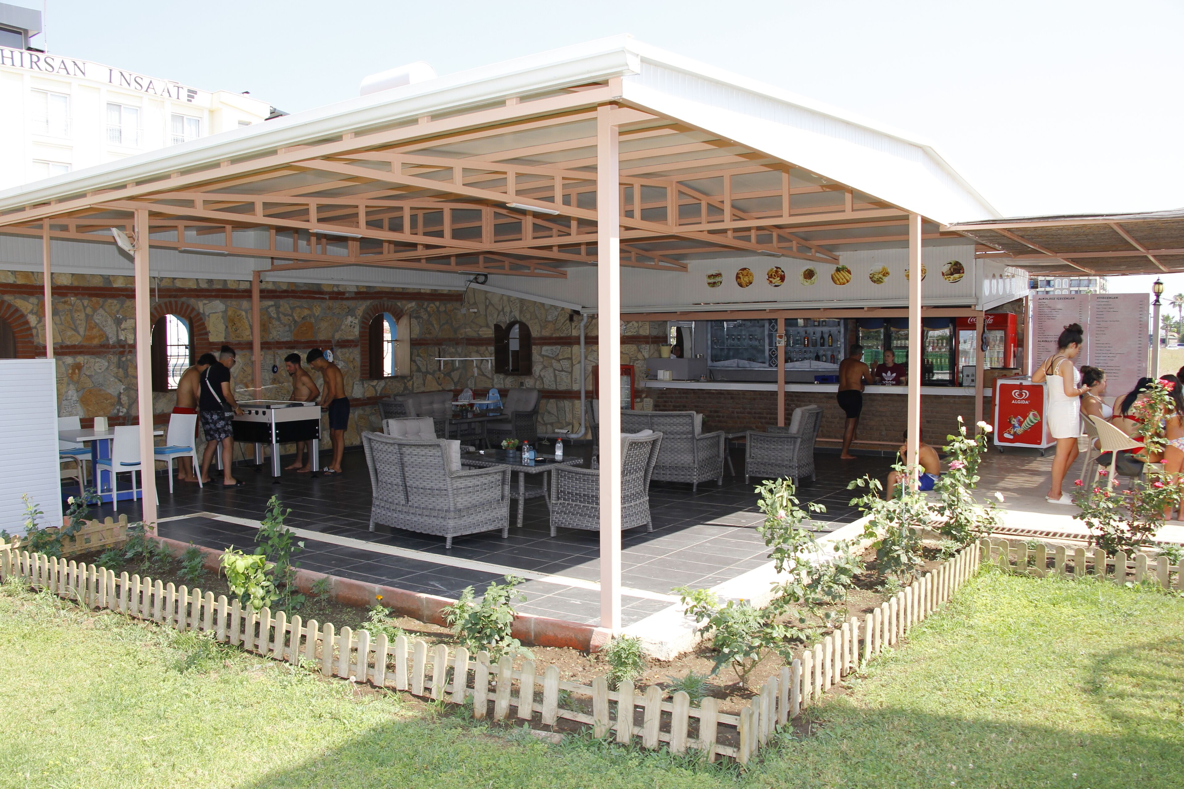 An outdoor patio area with wicker furniture, a bar, and a Coca-Cola refrigerator.
