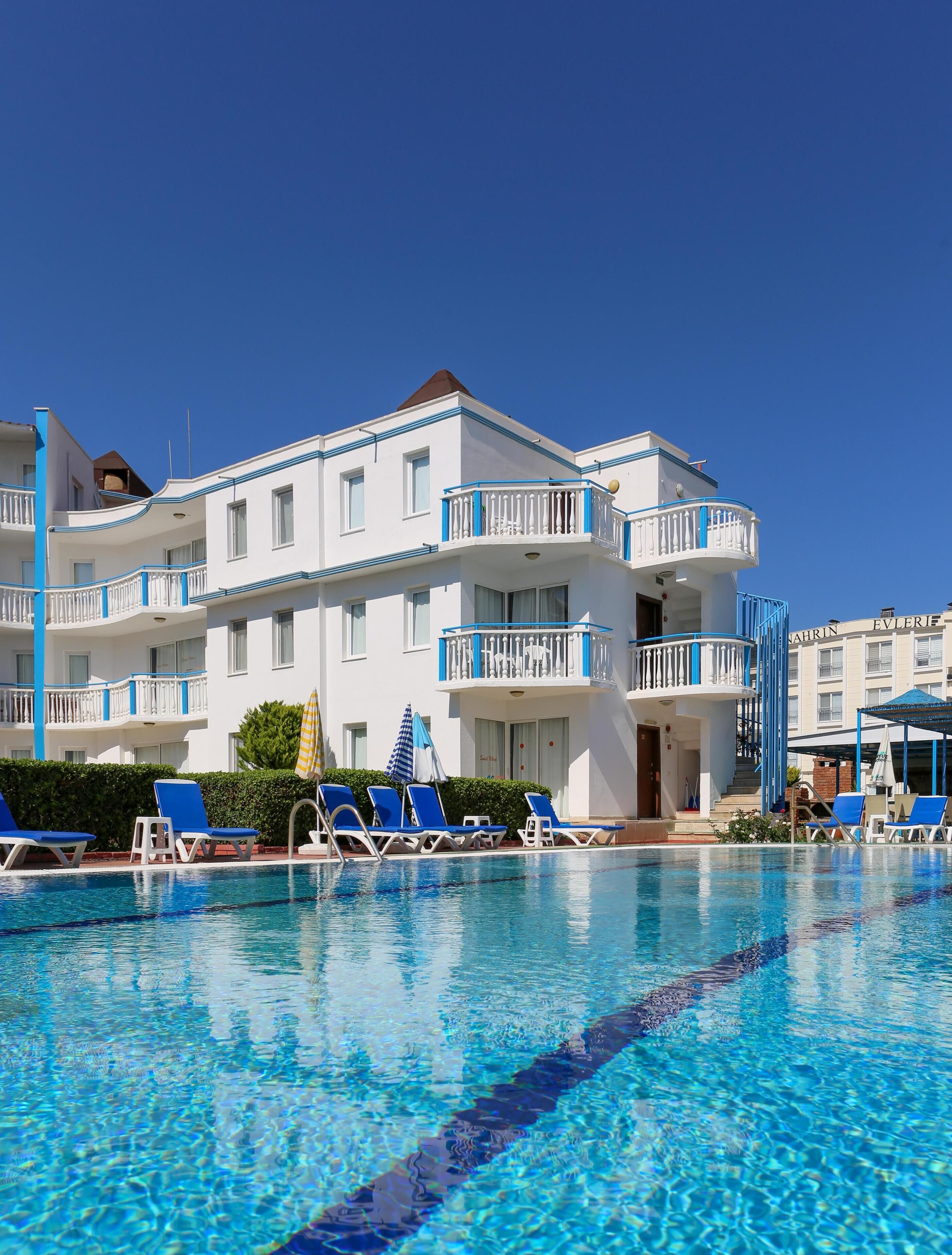 A hotel with a pool area, multiple balconies, and lounge chairs.