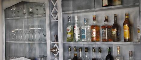 A bar area with shelves of liquor bottles and empty wine glasses.