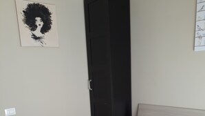 A neatly made bed with white linens, a checkered pillow, and a dark headboard. - 48 airport budget rooms (Pisa)