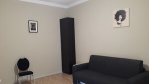 A room with a black sofa, a black chair, a tall black cabinet, and a framed picture on the wall. - 48 airport budget rooms (Pisa)