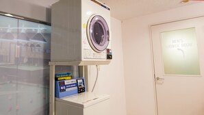 A laundry room with a front-loading washer and dryer, a CO/N washer, and a door labeled "MEN'S SHOWER ROOM". - Comics & CapsuleHotel COMICAP Sapporo (Sapporo)