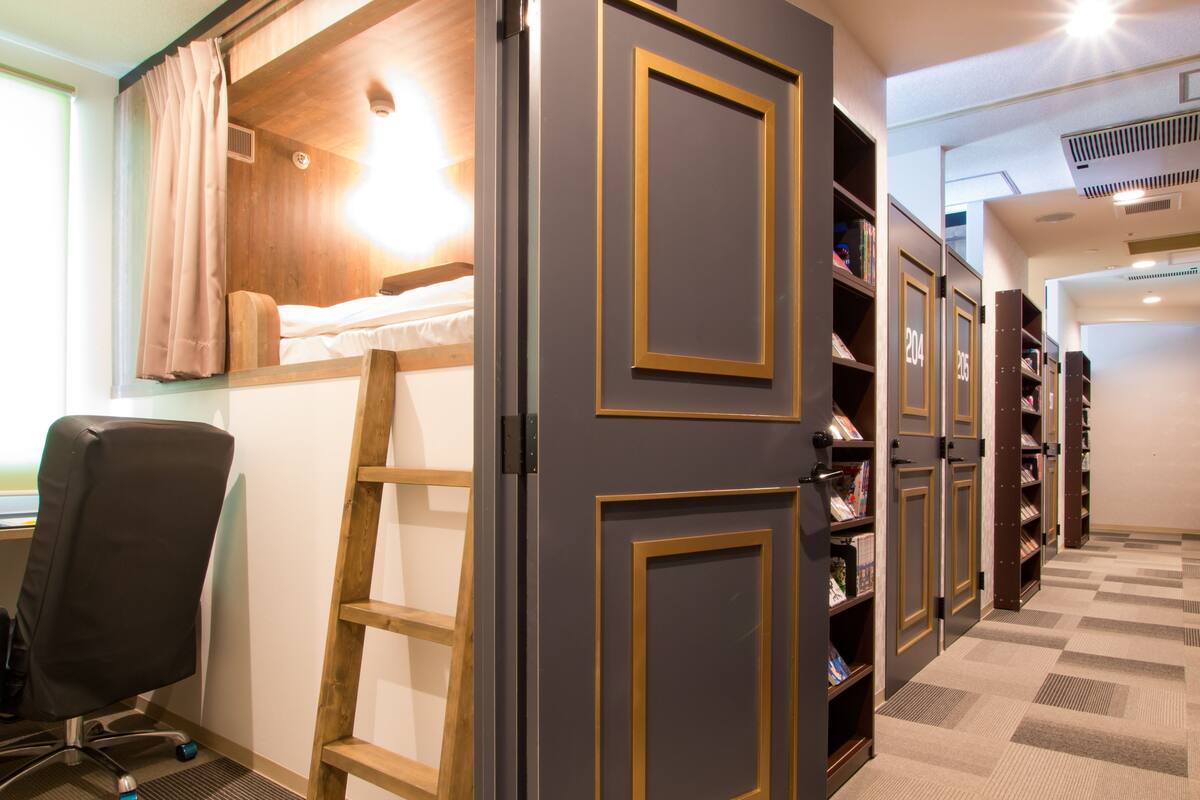 A room with a bunk bed, a desk, a chair, a ladder, and bookshelves.