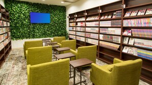 A library with green walls, bookshelves, and seating areas. - Comics & CapsuleHotel COMICAP Sapporo (Sapporo)