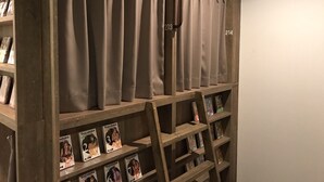 A wooden bookshelf with numbered curtains and magazines. - Comics & CapsuleHotel COMICAP Sapporo (Sapporo)