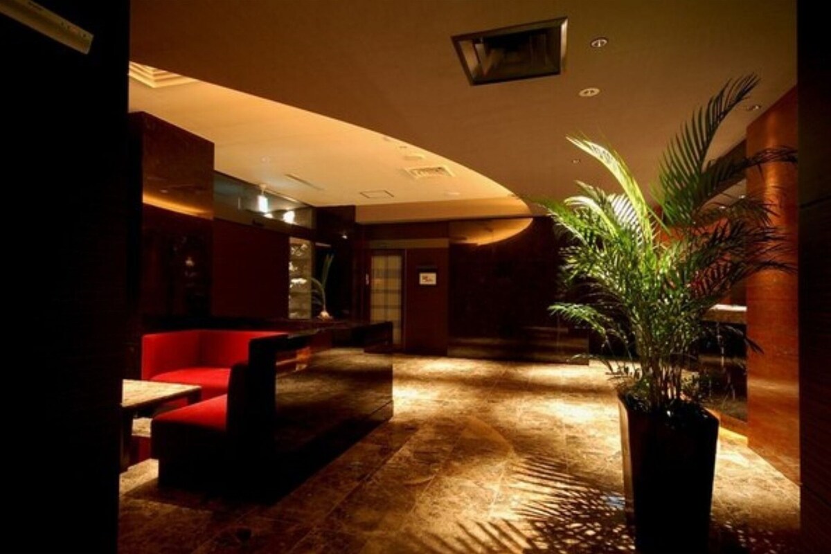 A hotel lobby with a red seating area, a potted plant, and a patterned floor.