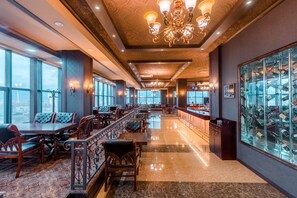 A spacious hotel lobby with a long bar, seating area, and a wine display. - The Grand Hill Hotel (Ulaanbaatar)