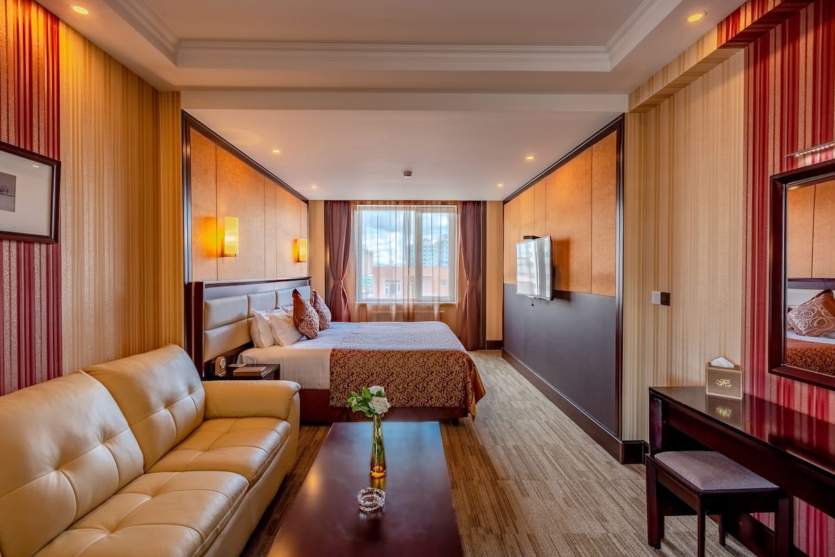 A hotel room with a bed, a sofa, a desk, and a TV.