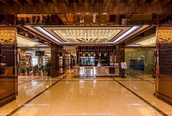 A lobby with a reception desk, potted plants, and a chandelier. - The Grand Hill Hotel (Ulaanbaatar)
