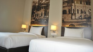 A hotel room with two beds, a wall-mounted lamp, and a large historical photo of a street scene. - The Grand Jade Hotel (Johor Bahru)