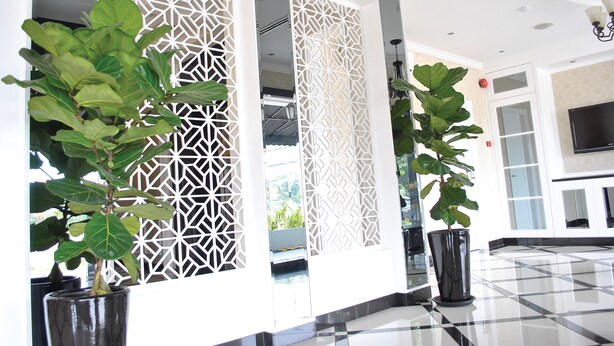 A lobby with a checkered floor, decorative white panels, and potted plants. - The Grand Jade Hotel (Johor Bahru)