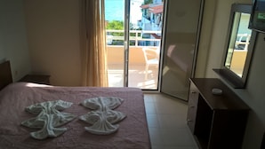 A hotel room with a bed, a dresser, a television, and a sliding glass door to a balcony. - Kyparissis Rooms (Kassandra)