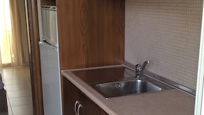 A kitchen with wooden cabinets, a stainless steel sink, and a built-in oven. - Kyparissis Rooms (Kassandra)