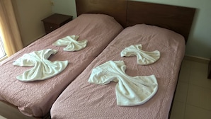 A hotel room with two beds, each with a pink textured bedspread and white towels folded on top. - Kyparissis Rooms (Kassandra)
