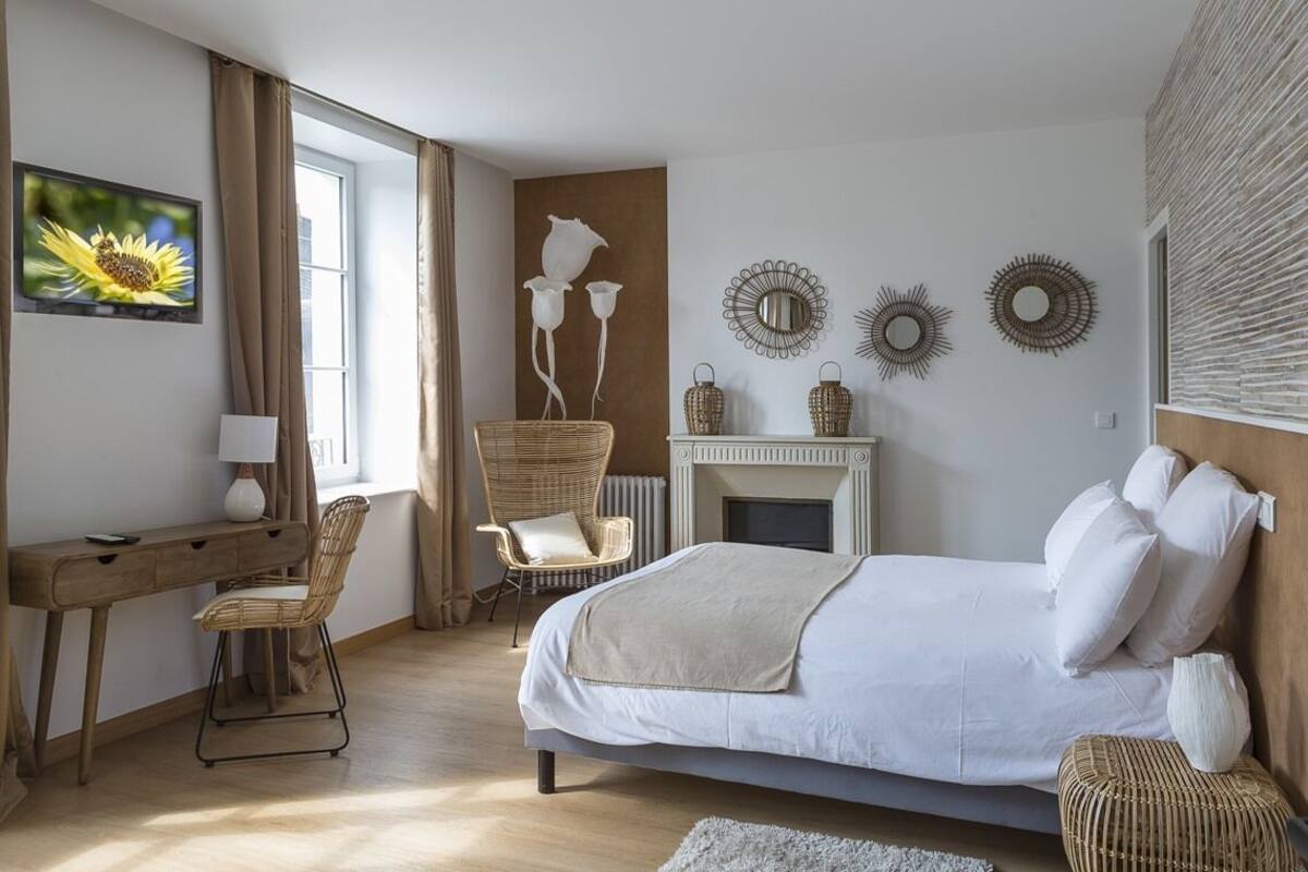 A bedroom with a bed, a desk, a chair, a fireplace, and wall decorations.