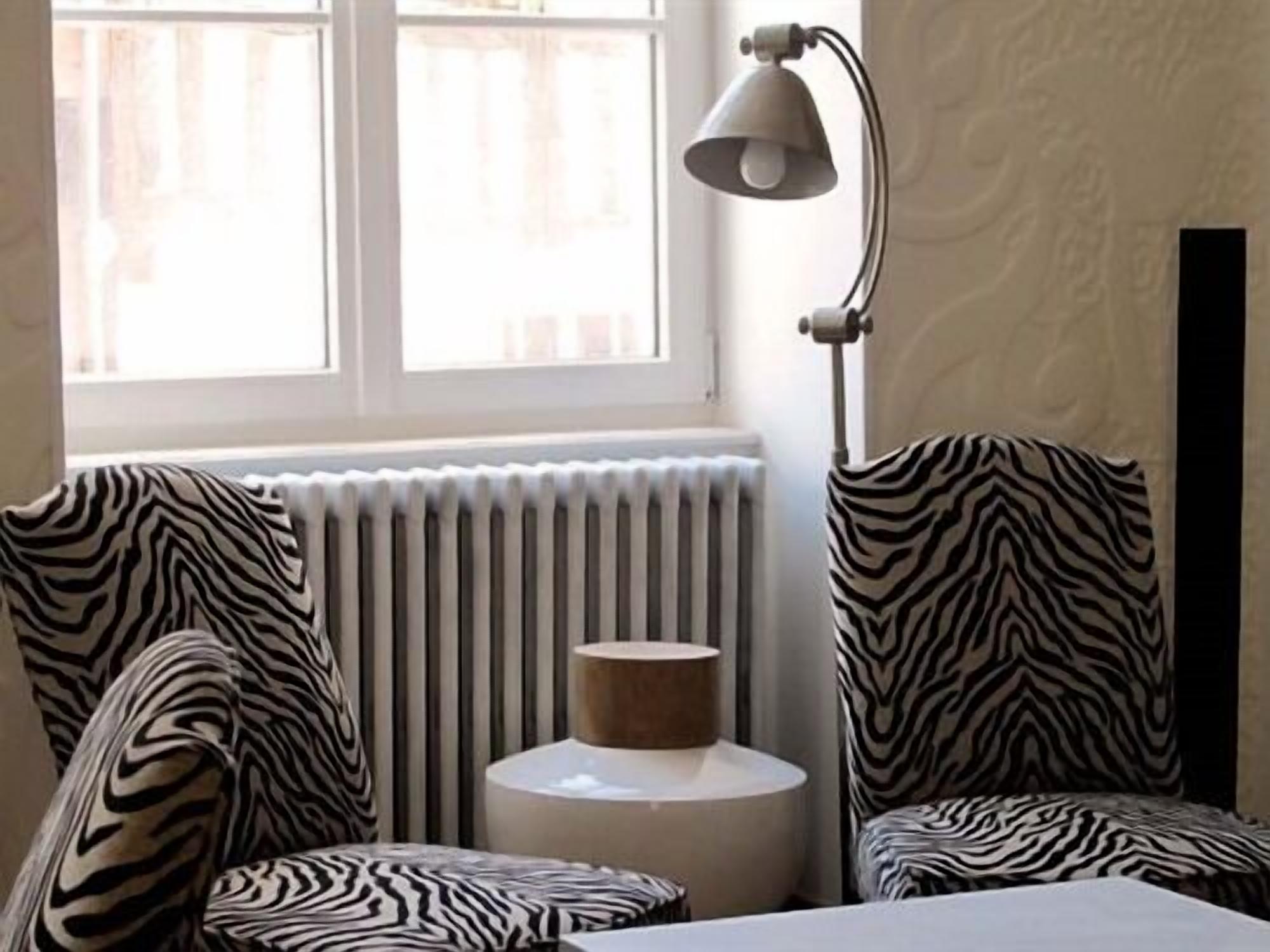 Ett rum med stolar i zebrastripe, ett element, en lampa och utsikt över omgivningen.