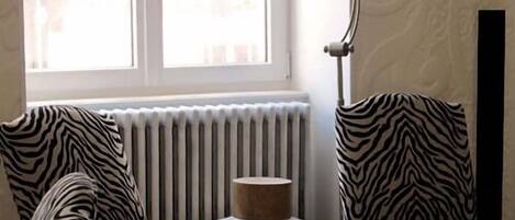 Ett rum med stolar i zebrastripe, ett element, en lampa och utsikt över omgivningen.