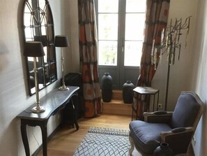 A room with a desk, chair, large window with curtains, and a radiator. - L'escale de Broglie (Broglie)