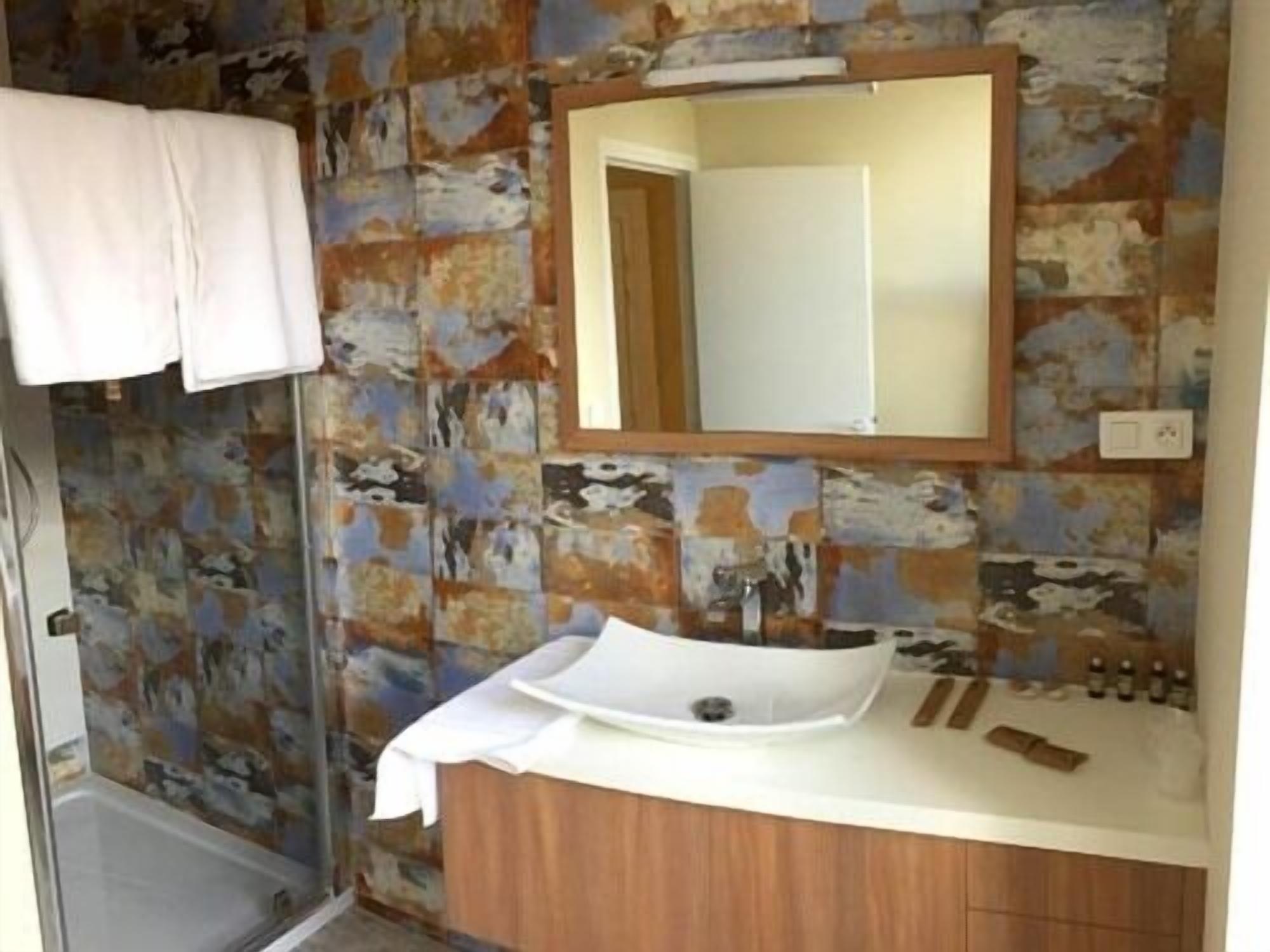 A bathroom with a white sink, a wooden vanity, and a mirror.