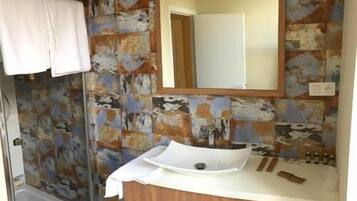 A bathroom with a white sink, a wooden vanity, and a mirror.