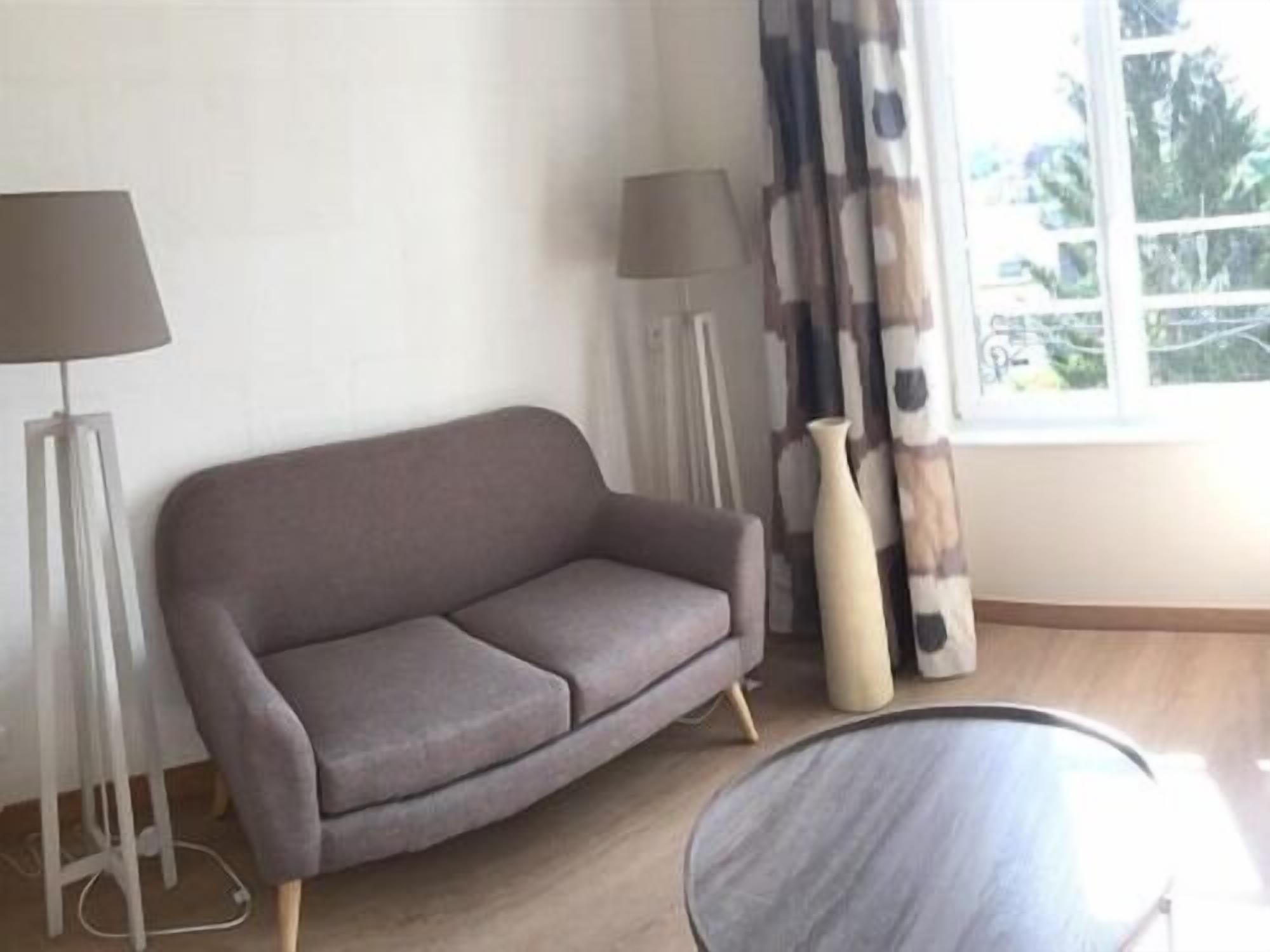 A living room with a grey sofa, a round table, and two floor lamps.