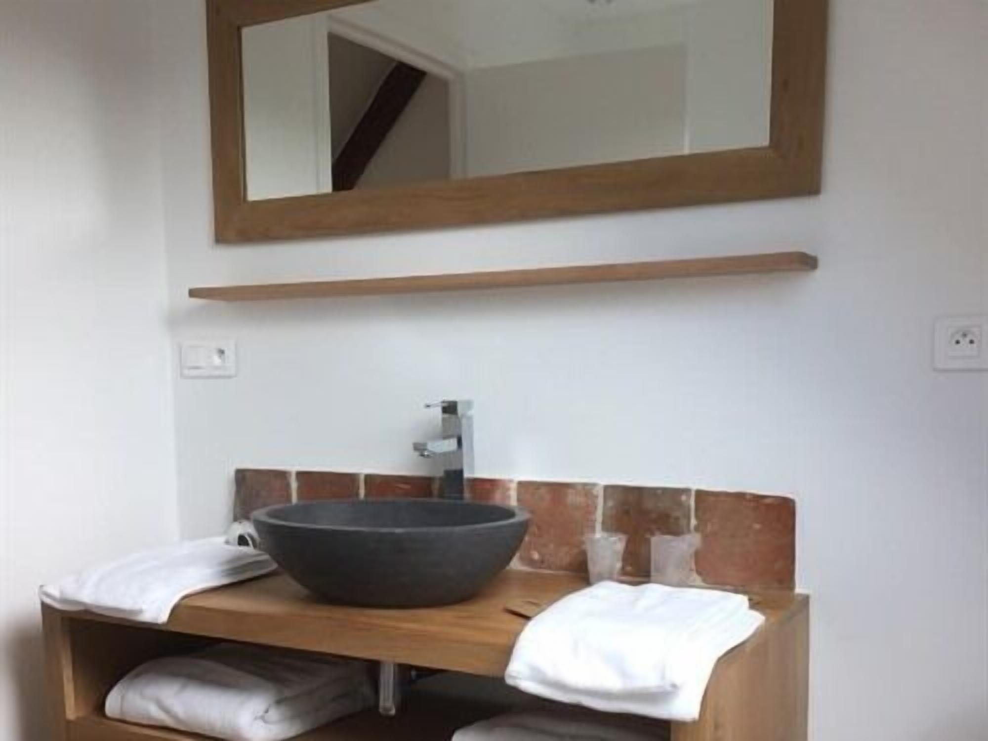 A bathroom with a wooden vanity, a large bowl sink, a mirror, and a towel rack.
