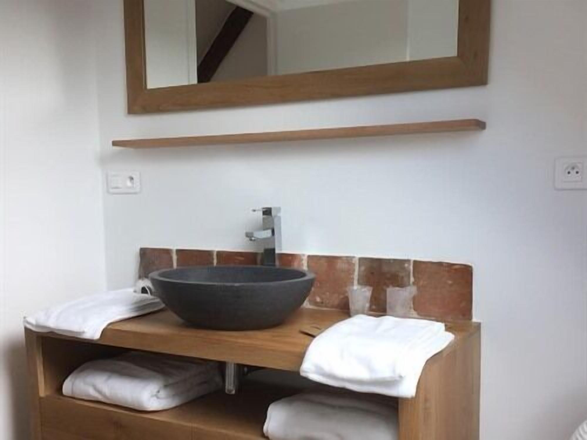 A bathroom with a wooden vanity, a large bowl sink, and a mirror above it.