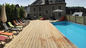 Una terraza de madera con sillas junto a la piscina.