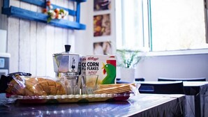 A table with a coffee maker, cereal, and bread.