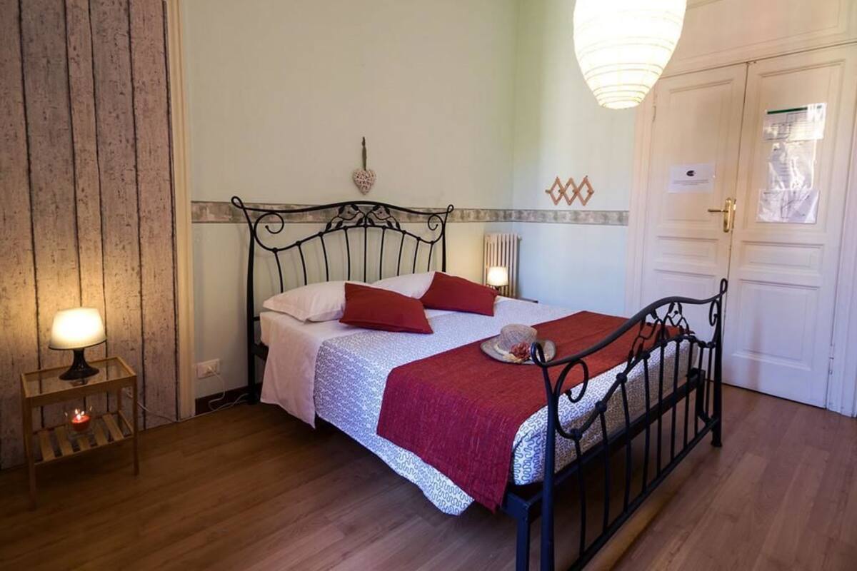 Een slaapkamer met een bed, bedlampen, een houten garderobe en een deur.