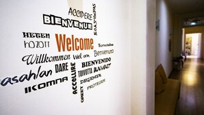 A hallway with a wall featuring multilingual 'Welcome' signs.